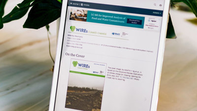 Tablet leaning on a plant pot. The sceen displays the WIREs journal homepage.