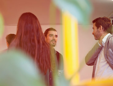 People gather together in a room, chatting and networking.