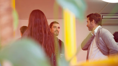 People gather together in a room, chatting and networking.