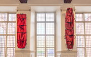 Two red pulks hang alongside each other in Main Hall at Society