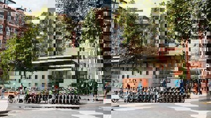 The Society's pavilion as people enter through the gate to the main entrance. In front of the entrance is a row of rentable e-bikes.