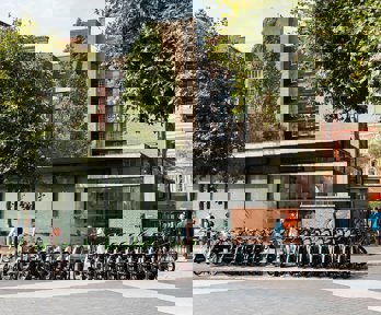 The Society's pavilion as people enter through the gate to the main entrance. In front of the entrance is a row of rentable e-bikes.