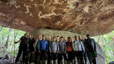 A large group in a cave with rock paintings.