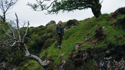Ted standing amongst moss and trees with video recording equipment