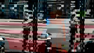 Two family members standing next to a bus hugging each other.