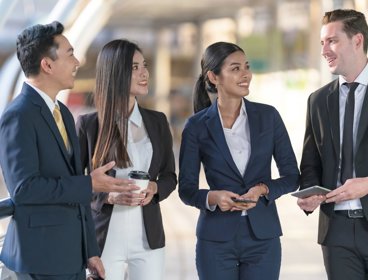 Four people in business suits stood talking.