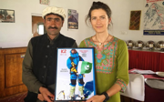 Two people posing holding poster of mountain climber, in Pakistan. 