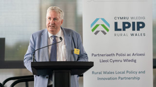 Michael Woods speaking behind a lectern at a Rural Wales Local Policy and Innovation Partnership (LPIP) event.
