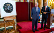 Two people in formal wear on a podium looking at a framed poster that says Astra Carta.