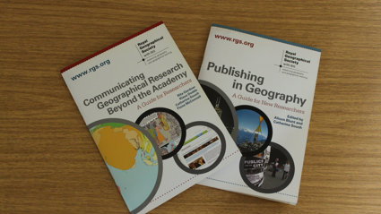 Two booklets on top of a wooden surface. The text on one booklet reads 'Communicating Geographical Research Beyond the Academy' and the other reads 'Publishing in Geography'.