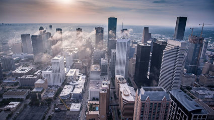Drone view of city skyscrapers with low clouds between the buildings.