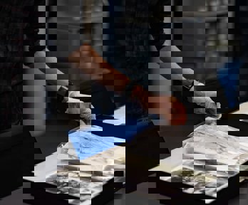 A researcher wearing archival gloves viewing historic photographs in a folder