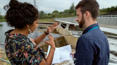 two engineers standing next to dam looking at paperwork