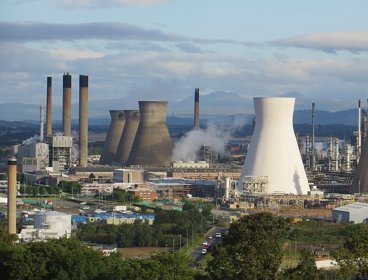 An aerial view of a power station, showing chimneys and smoke