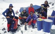 Group of explorers on an expedition resting at base camp in a mountainous, snowy area.