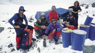 Group of explorers on an expedition resting at base camp in a mountainous, snowy area.