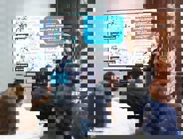 A conference delegate presenting their work to other conference delegates