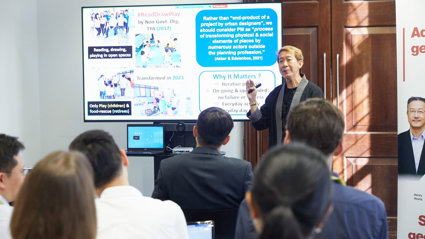 A conference delegate presenting a slide to other conference delegates.