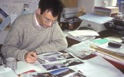 Man sitting in an office looking at pictures of snowy mountains.