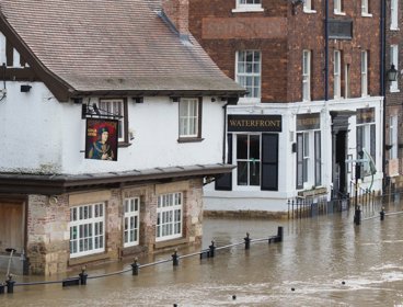 Flooded street with water rising towards windows of brick buildings. 