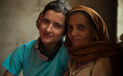 A young person posing next to an older person wearing a brown headcsarf. 