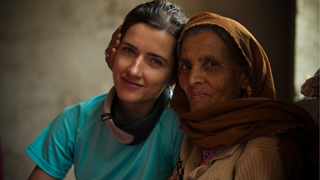 A young person posing next to an older person wearing a brown headcsarf. 