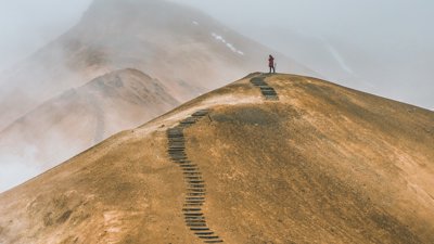 Person standing at the top of the hill with winding path below