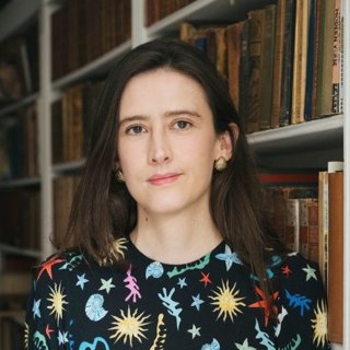 Sofia Castelló standing in front of a bookcase with old books.