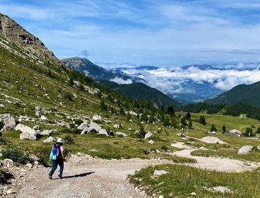 A person walking along a gravel path in a mountain valley.