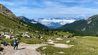 A person walking along a gravel path in a mountain valley.