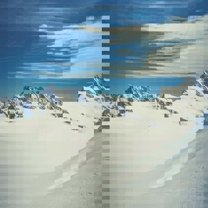 A snow covered glacier with the tips of mountains poking through the snow and ice