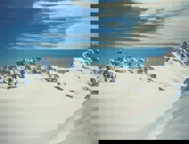 A snow covered glacier with the tips of mountains poking through the snow and ice