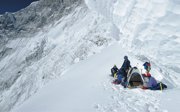 Men in a snowy, barren and mountainous area resting at an improvised camp.