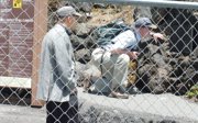 Two people behind a metal fence looking at grey rocks