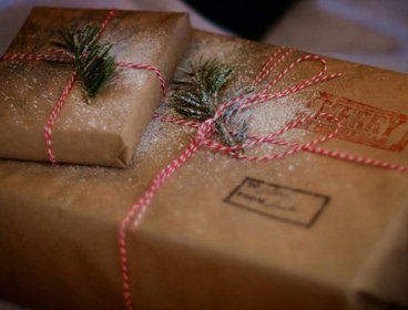 Two presents wrapped in brown paper and decoated with dusted snow.