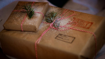 Two presents wrapped in brown paper and decoated with dusted snow.