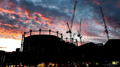 Tower crane and high-rise building silhouettes under a blue, pink and orange sky.