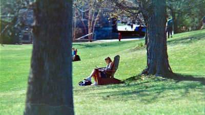A person sitting in a lawn chair working on a laptop.