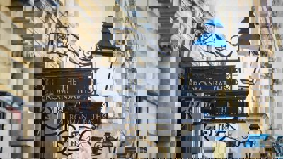 Close up of a row of buildings with signage of 'The Roman Baths' with ornate lanterns.