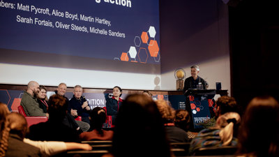 Panel of speakers on stage in the Ondaatje Theatre at Explore 2022. 