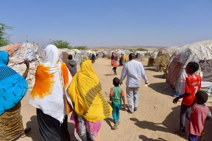 A group of people walkng through a tented settlement