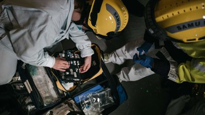 Two people wearing yellow hard hats opening a first aid equipment kit