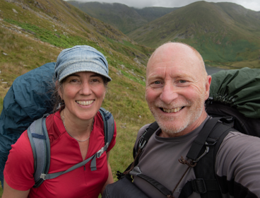 Rob and Harriet Fraser with backpacking gear taking a selfie in the mountains.