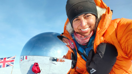 Preet Chandi in the South Pole taking a selfie next to a reflective globe. A Union Jack flag is visisble out of focus left of the globe.