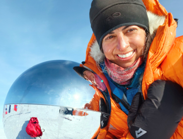 Preet Chandi in the South Pole taking a selfie next to a reflective globe. A Union Jack flag is visisble out of focus left of the globe.