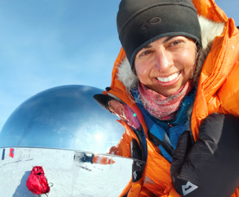 Preet Chandi in the South Pole taking a selfie next to a reflective globe. A Union Jack flag is visisble out of focus left of the globe.