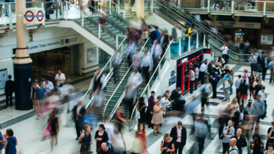 Large numbers of people rush through Liverpool Street station whilst others stand, presumably waiting for their train. those moving are captured as blurs going up and down the stairs, esclators and walking accross the station floor.