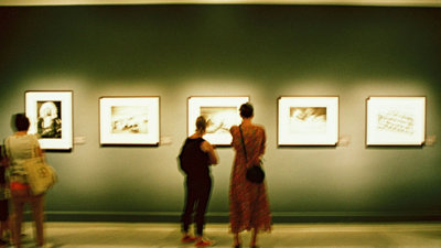 Two people looking at a picture in an exhibition gallery.
