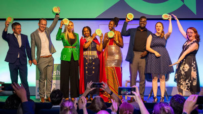 People on stage holding up medals in celebration at an awards ceremony. 