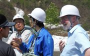 Three people in white hard hats and Murray Gray in a cap standing in natural landscape.